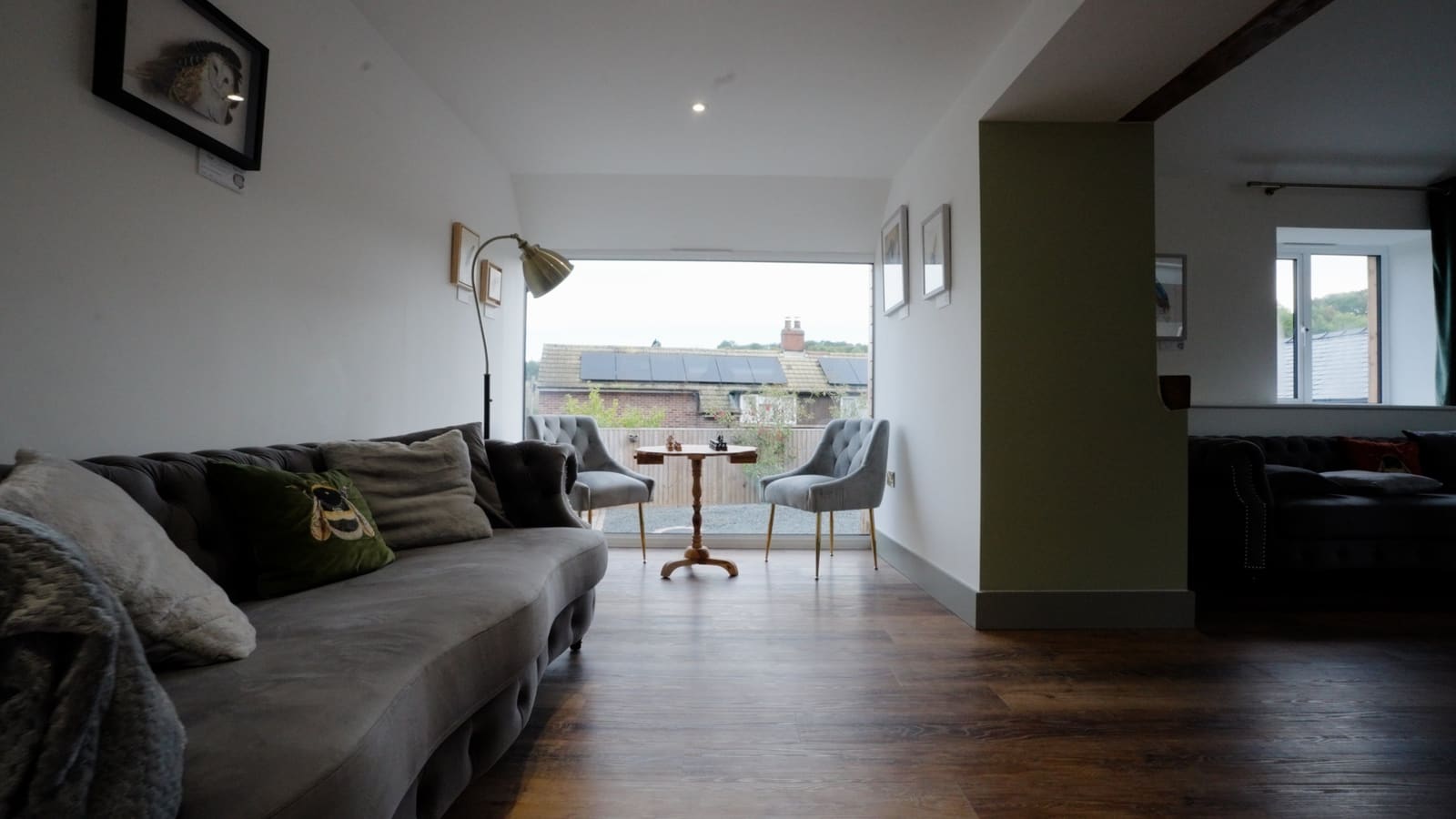 A quiet corner with a velvet sofa and two chairs at a chess table by a picture window.