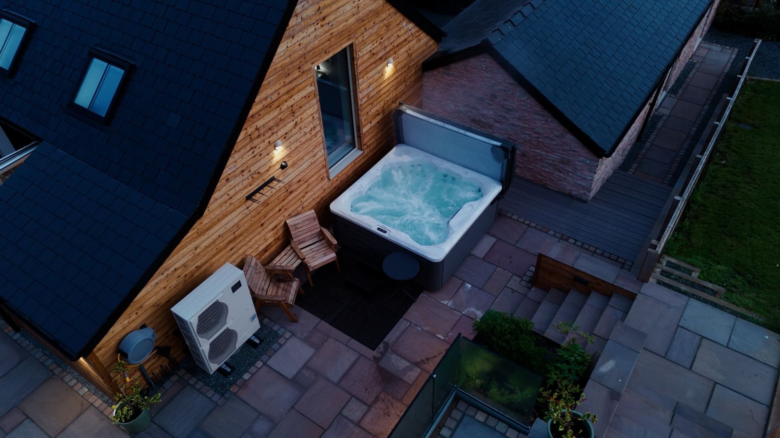 The private hot tub from above, beside the timber-clad gable and two wooden chairs.